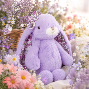 Friendly Karina Floral knuffelkonijn van Bukowskiknuffels.nl met lavendelkleurige pluche, bloemenprint in de hangoren, als strik en onder de pootjes, zittend in bloemenveld