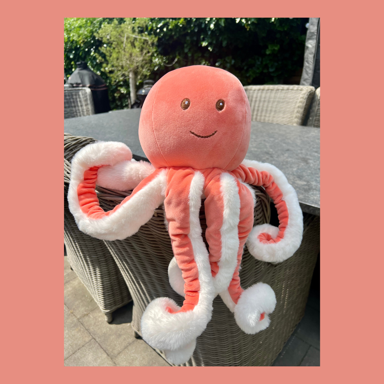 Ninky XL octopusknuffel van Bukowski Sweden met opkrullende tentakels – 55 cm, roze/oranje met wit in een sfeerfoto waar de krullende tentakels goed te zien zijn